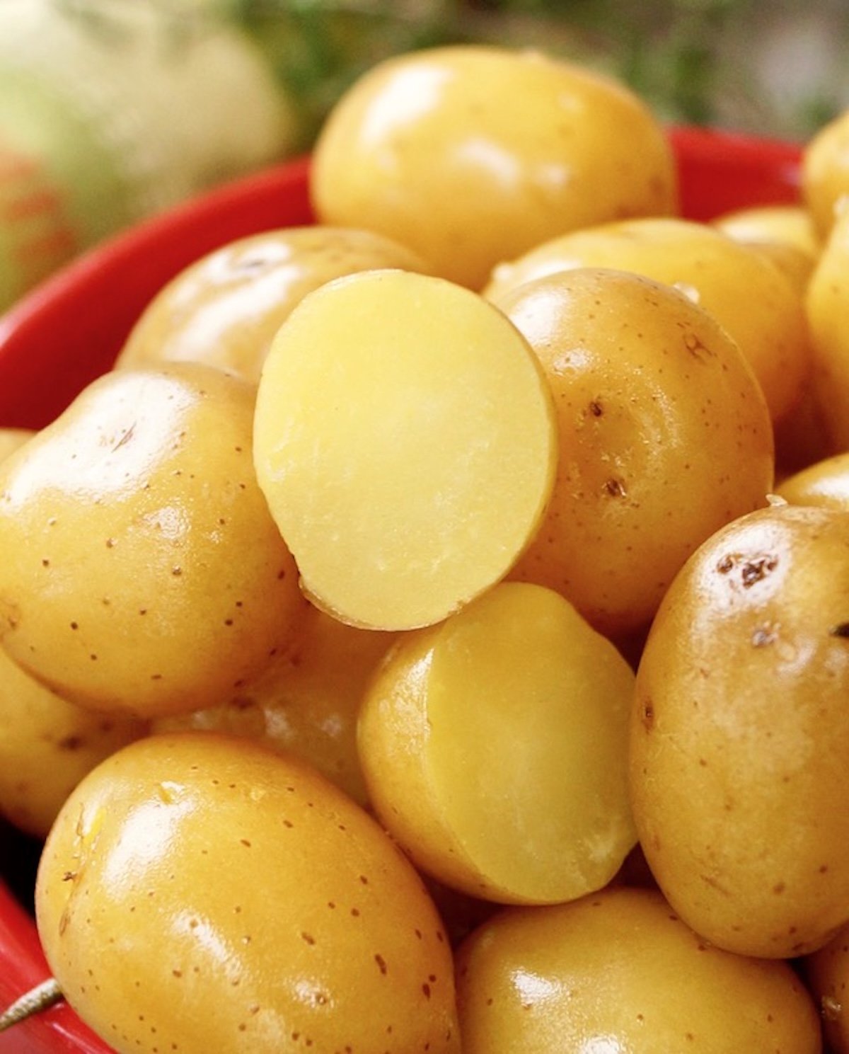 Pile of confit baby potatoes with one sliced in half.