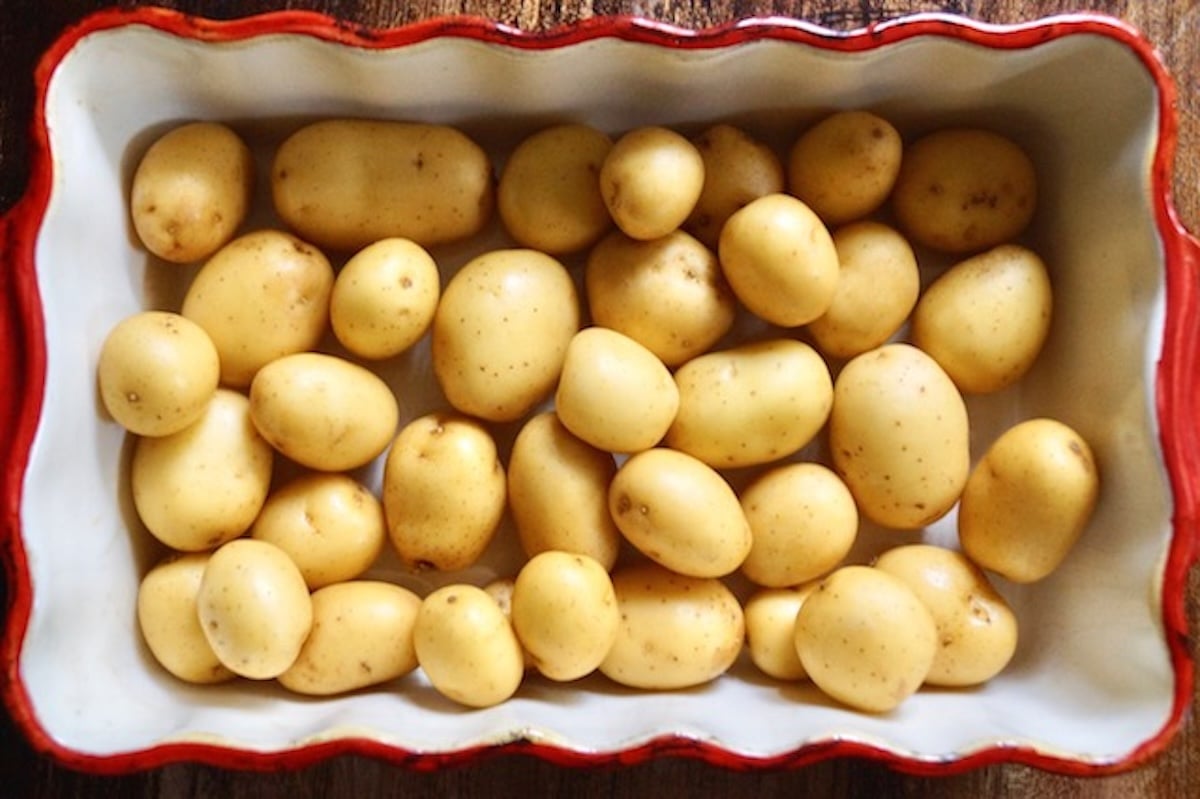 Raw Pee Wee potatoes in a red-rimmed baking dish.
