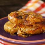 Slice of smashed potato casserole with caramelized on a purple plate.