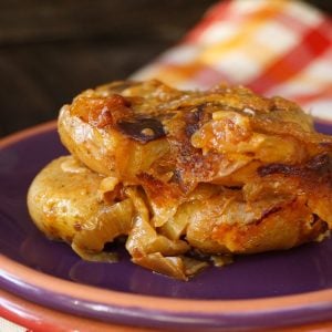 Slice of smashed potato casserole with caramelized on a purple plate.