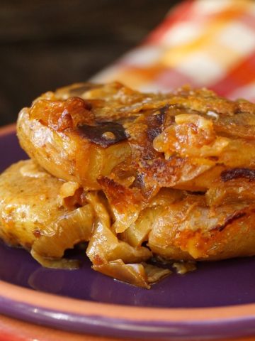 Slice of smashed potato casserole with caramelized on a purple plate.