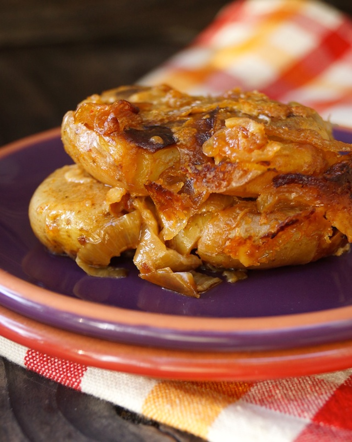 Slice of smashed potato casserole with caramelized on a purple plate.
