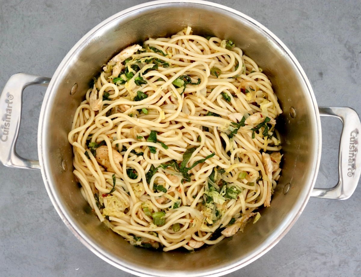 Chinese-Longevity-Noodles-Recipe Large pot with cooked Chinese noodles mixed with stir-fried cabbage, Gai Lan and a spicy sauce.