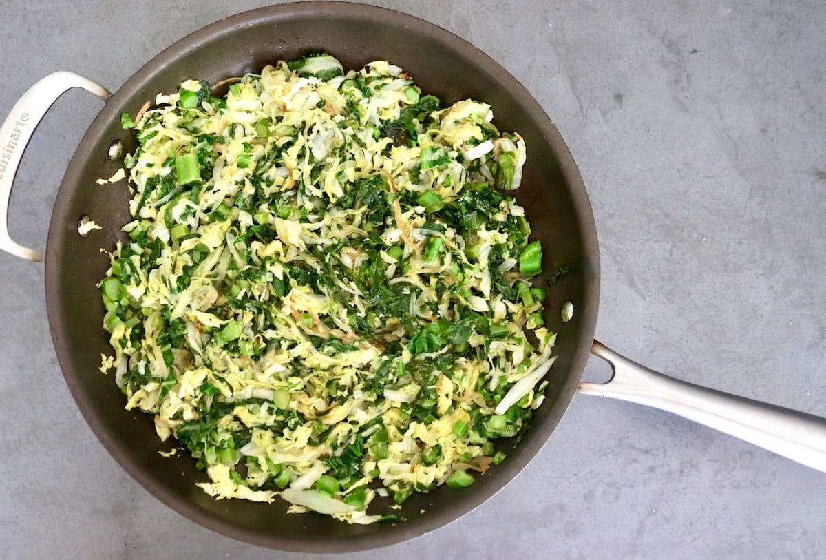 Chinese-Longevity-Noodles-Recipe Sautรฉed cabbage and Gai Lan, onion, garlic and ginger, in a large sautรฉ pan.