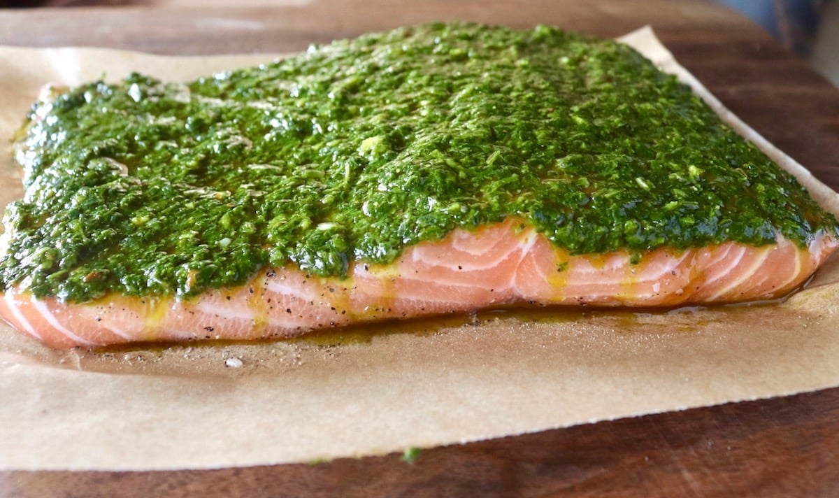 Large fillet of salmon with a thin spread of chimichurri on top.