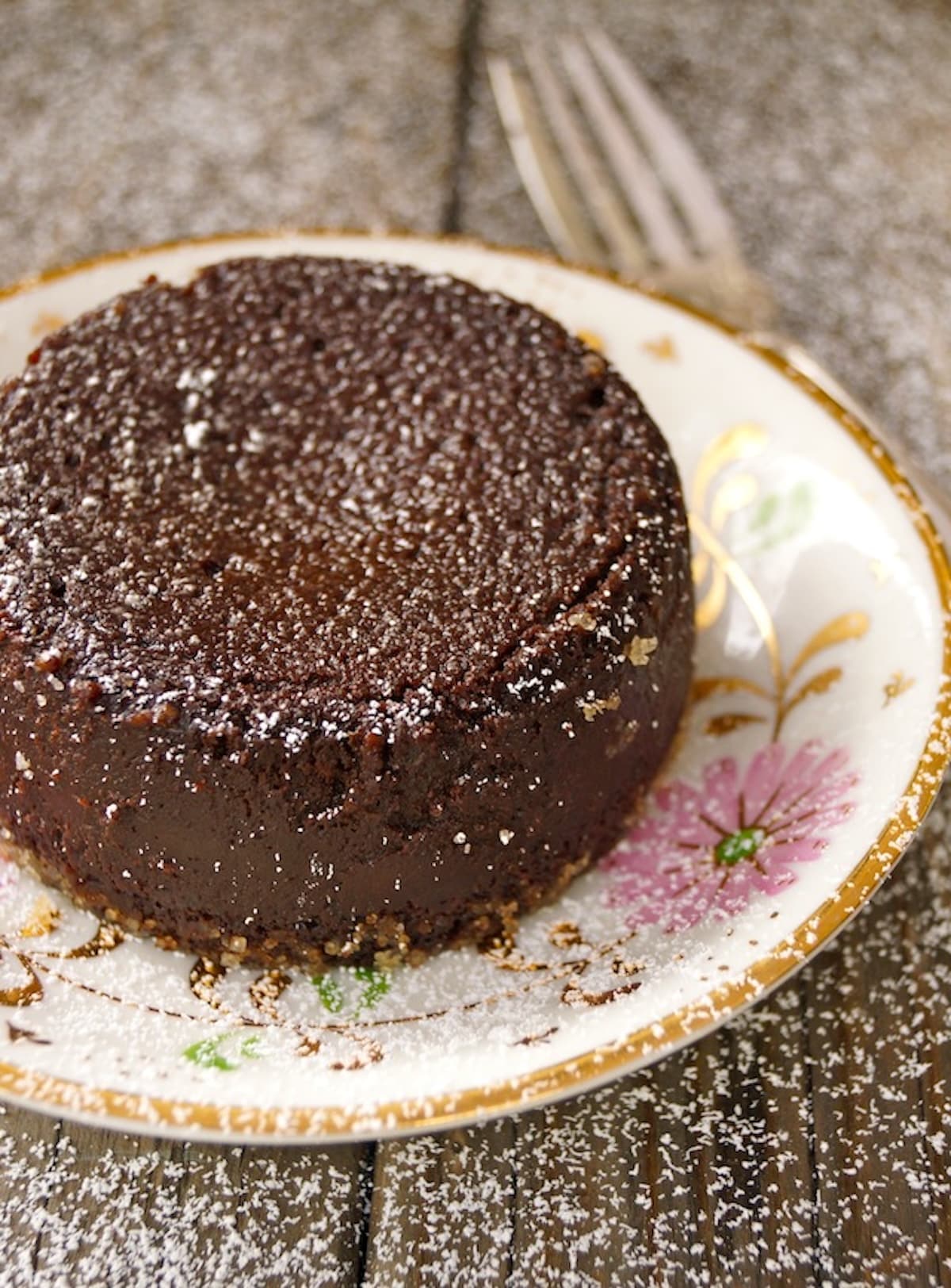 Flourless-Chocolate-Decadence-KahlĂșa-Cake Inverted individual chocolate flourless espresso cake on pretty pink and gold china plate.