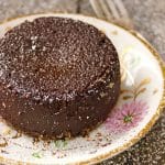 Flourless Chocolate Kahlua Espresso Decadence Cake on a pretty, gold-rimmed plated with pink flowers, dusted with powdered sugar.