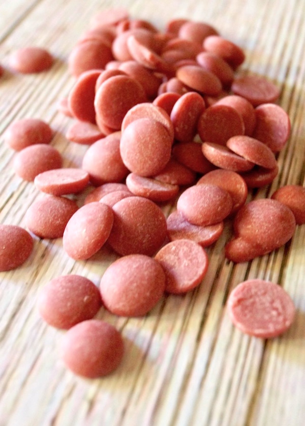 Pile of pink (Ruby) chocolate chips on a white wood background.