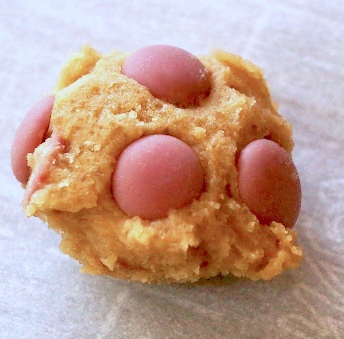 One ball of Ruby Chocolate Chip Cookie dough on white parchment paper.