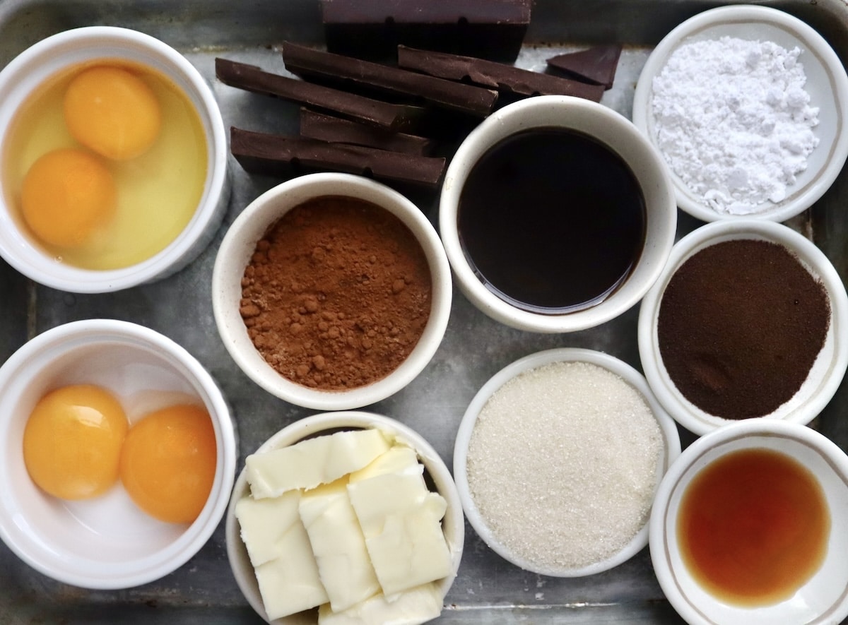 Flourless Chocolate-Cake-with-KahlĂșa-and-Espresso Ingredients for flourless chocolate espresso cakes including cocoa powder, espresso powder, eggs, KahlĂșa, granulated sugar, vanilla, butter, powdered sugar, and chocolate bar.