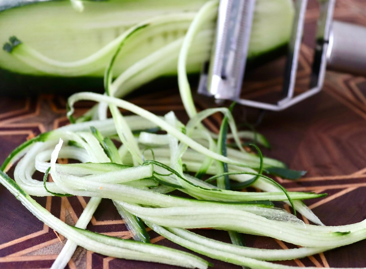 Julienne peeler with a cucuber cut into julienne (thin long) slices.