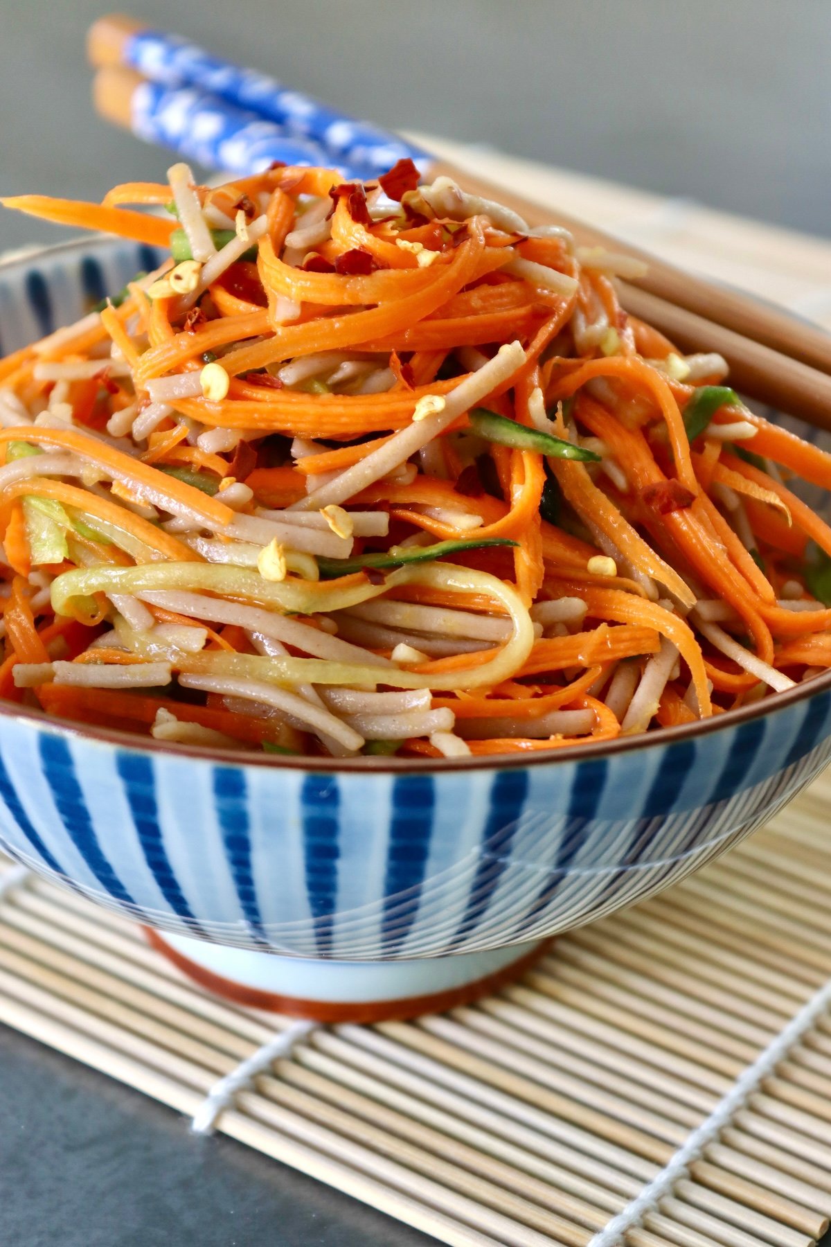 Cold-Soba-Noodle-Salad-with-Carrots Blew and white bowl filled very high with soba noodles and carrot noodles.