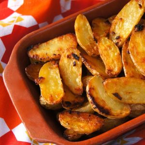 Top view of a rectangular terra cotta dish with crispy fingerling potatoes.