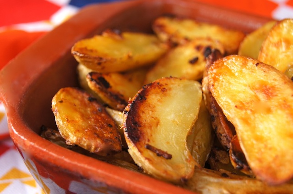 Close up of rectangular terra cotta dish with crispy fingerling potatoes.