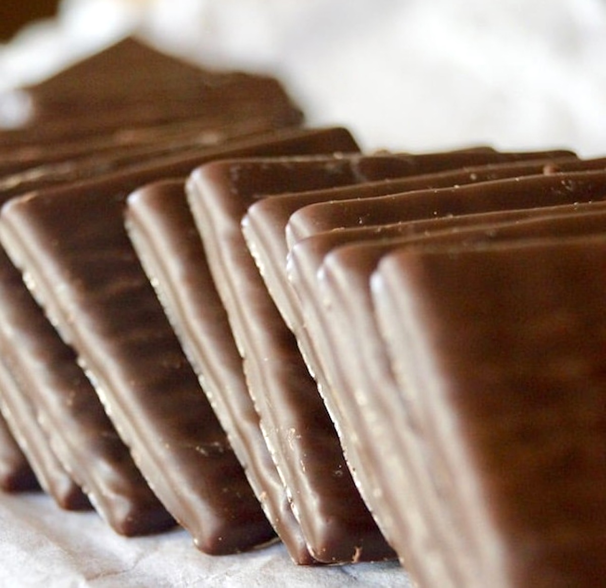 Several After Eight chocolate mints in a neatly stacked row.