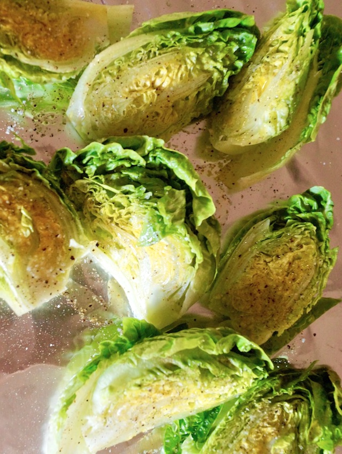 Grilled-Little-Gem-Lettuce-Salad A few oiled heads of little gem lettuce cut in half on a sheet pan.