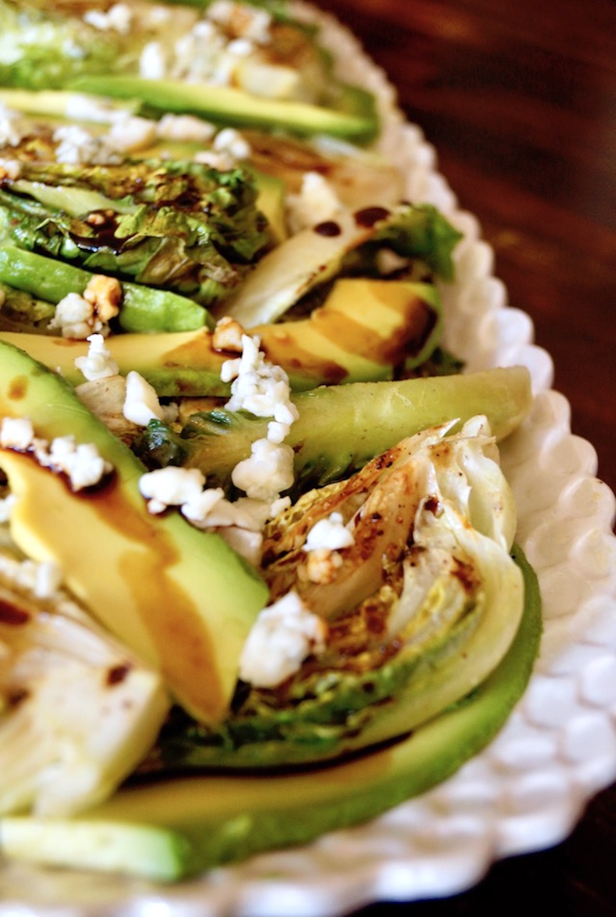 Grilled-Little-Gem-Lettuce-Salad Grilled Little Gem Salad on a white plate with bits of blue cheese, balsamic and avocado.
