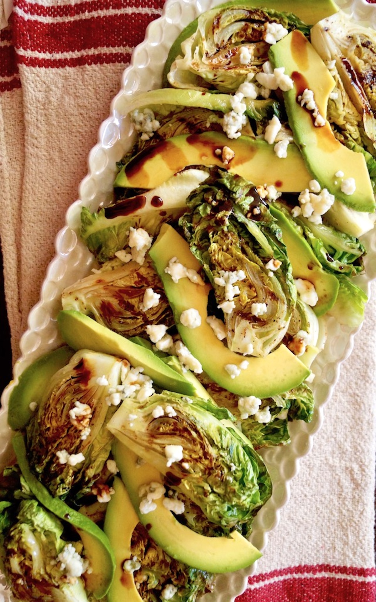 Grilled-Little-Gem-Lettuce-Salad Little Gem Salad on a white narrow plate with avocado and Goat cheese.