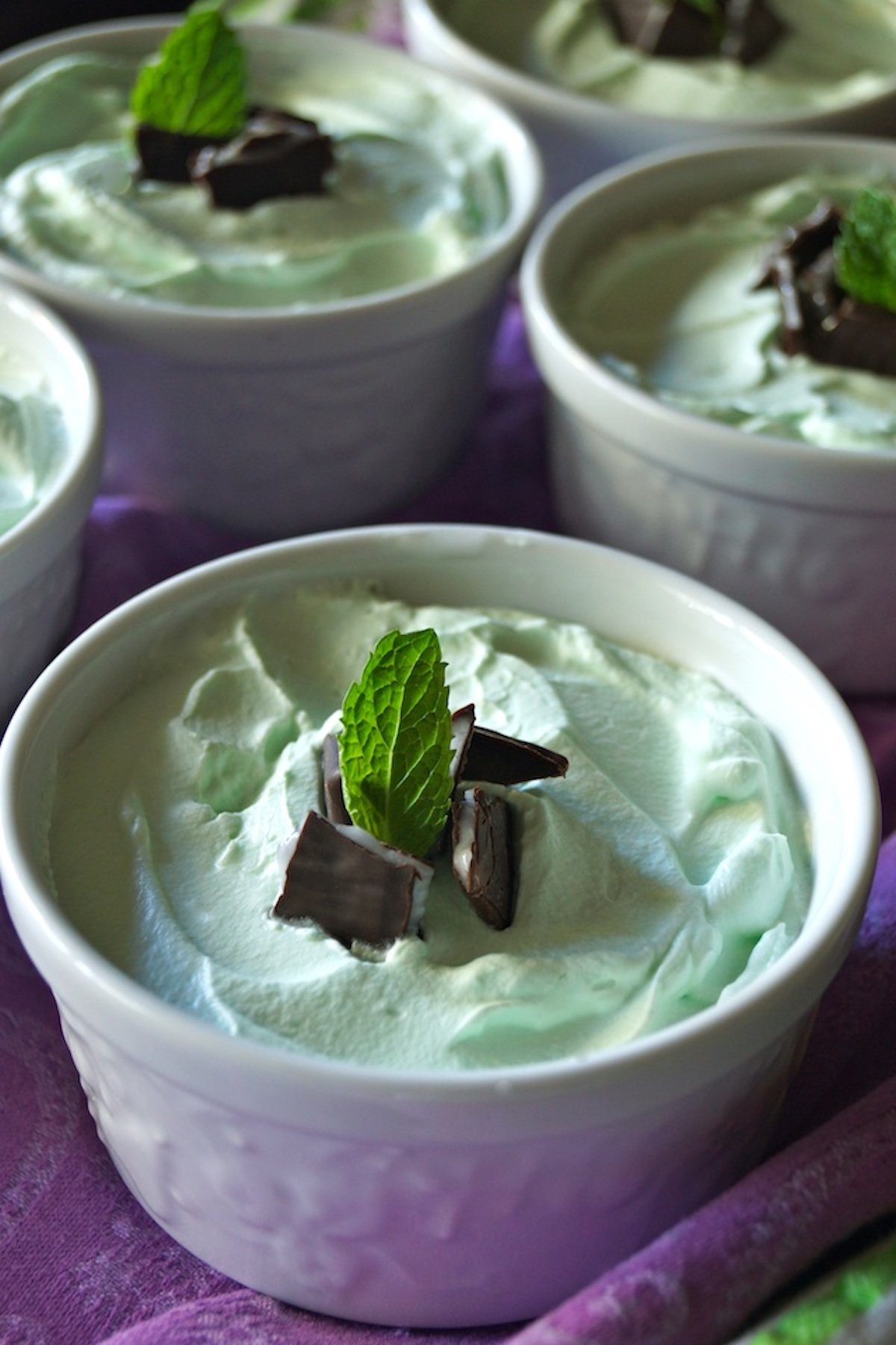 Individual Grasshopper Mousse Pies in pretty white ramekins with fresh mint leaves.
