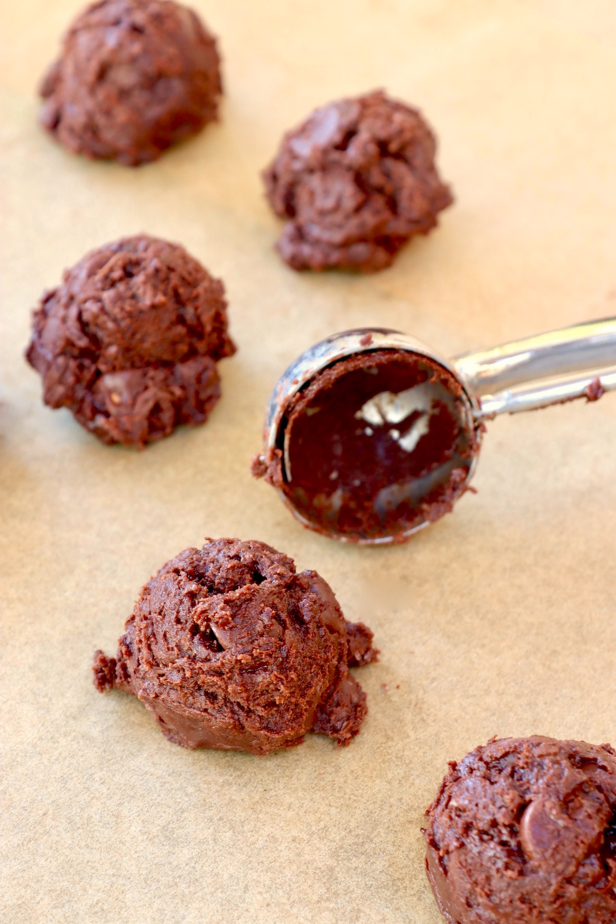 raw nutella cookie batter on parchment paper with cookie scoop