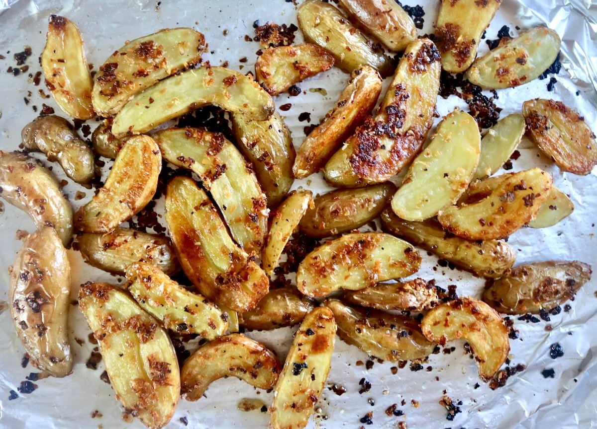 Crispy golden halved fingerling potatoes on foil on a sheet pan.