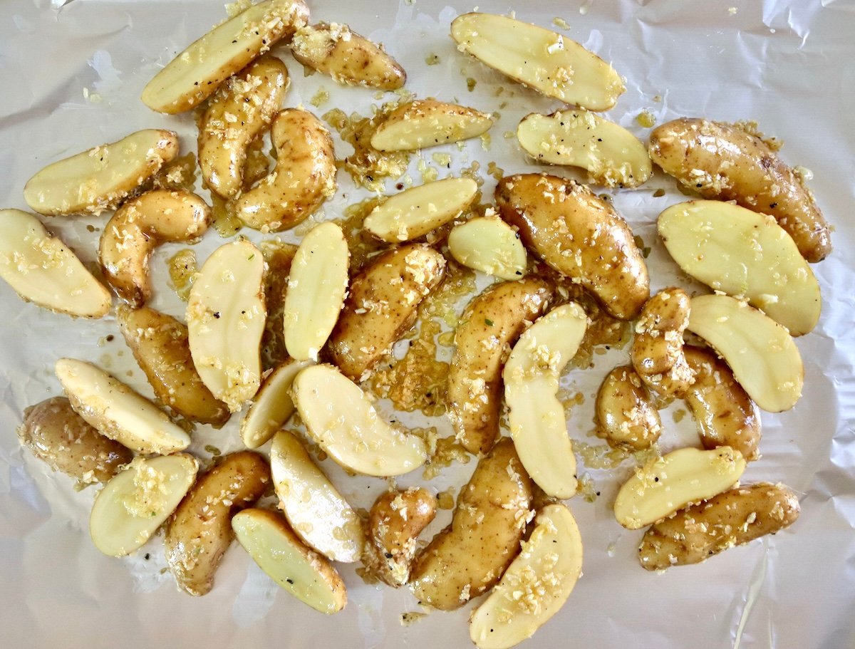 Olive oil-coated, halved fingerling potatoes on foil.