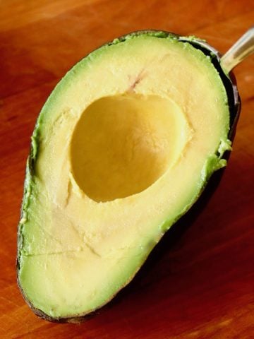 Half an avocado in a spoon without the pit.