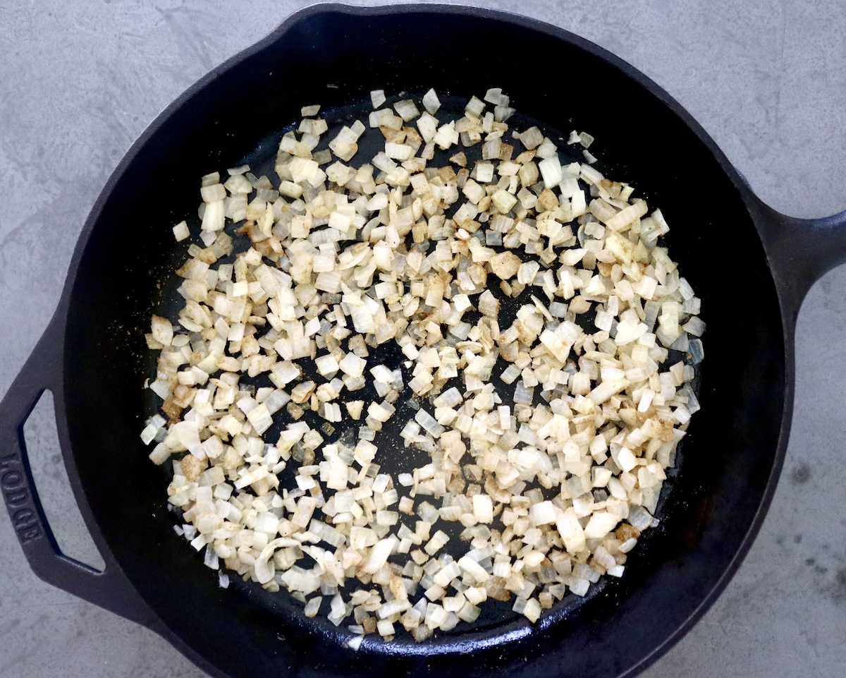 Diced, sauteed onions in a cast iron skillet.