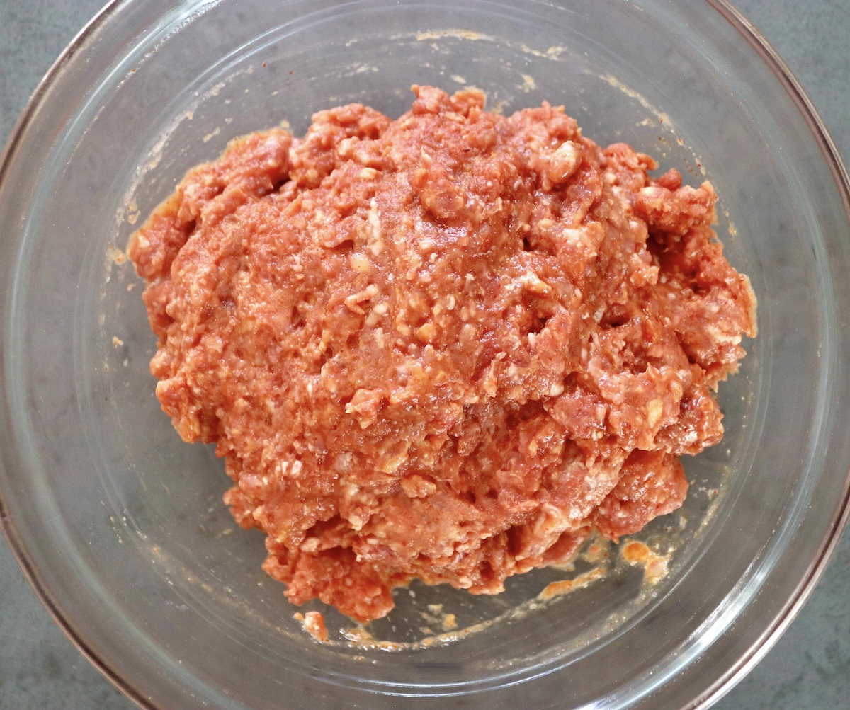 Sriracha-honey meatball mixture in glass bowl.