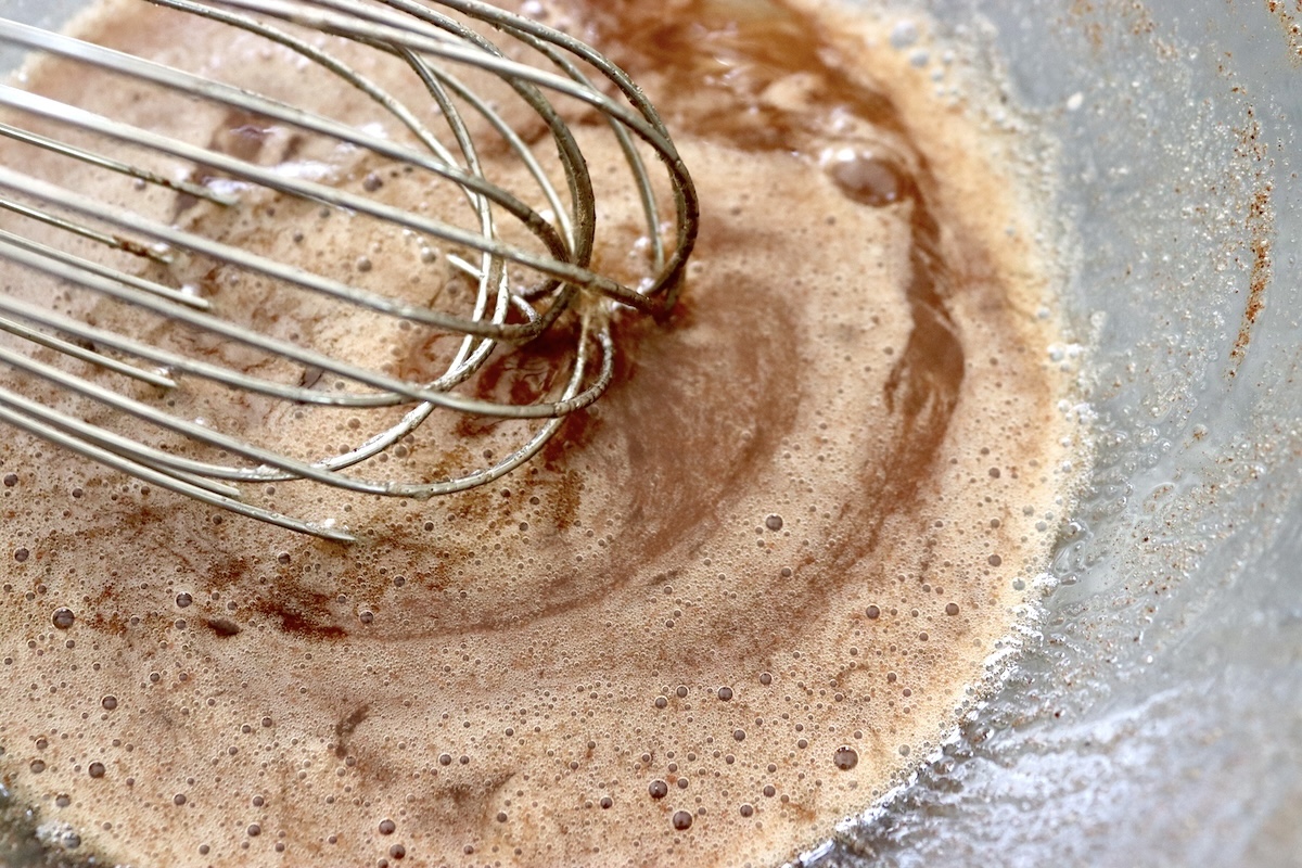 Batter for granola cookies in a mixing bowl with a whisk.