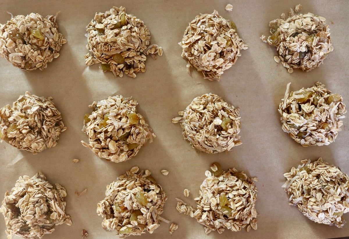 Several balls of raw granola cookies on a baking sheet.