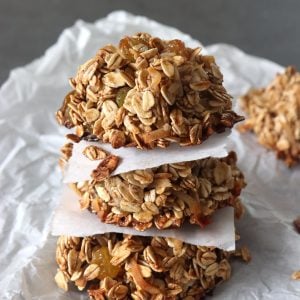 Stack of 3 granola cookies with a square of parchment between each one.