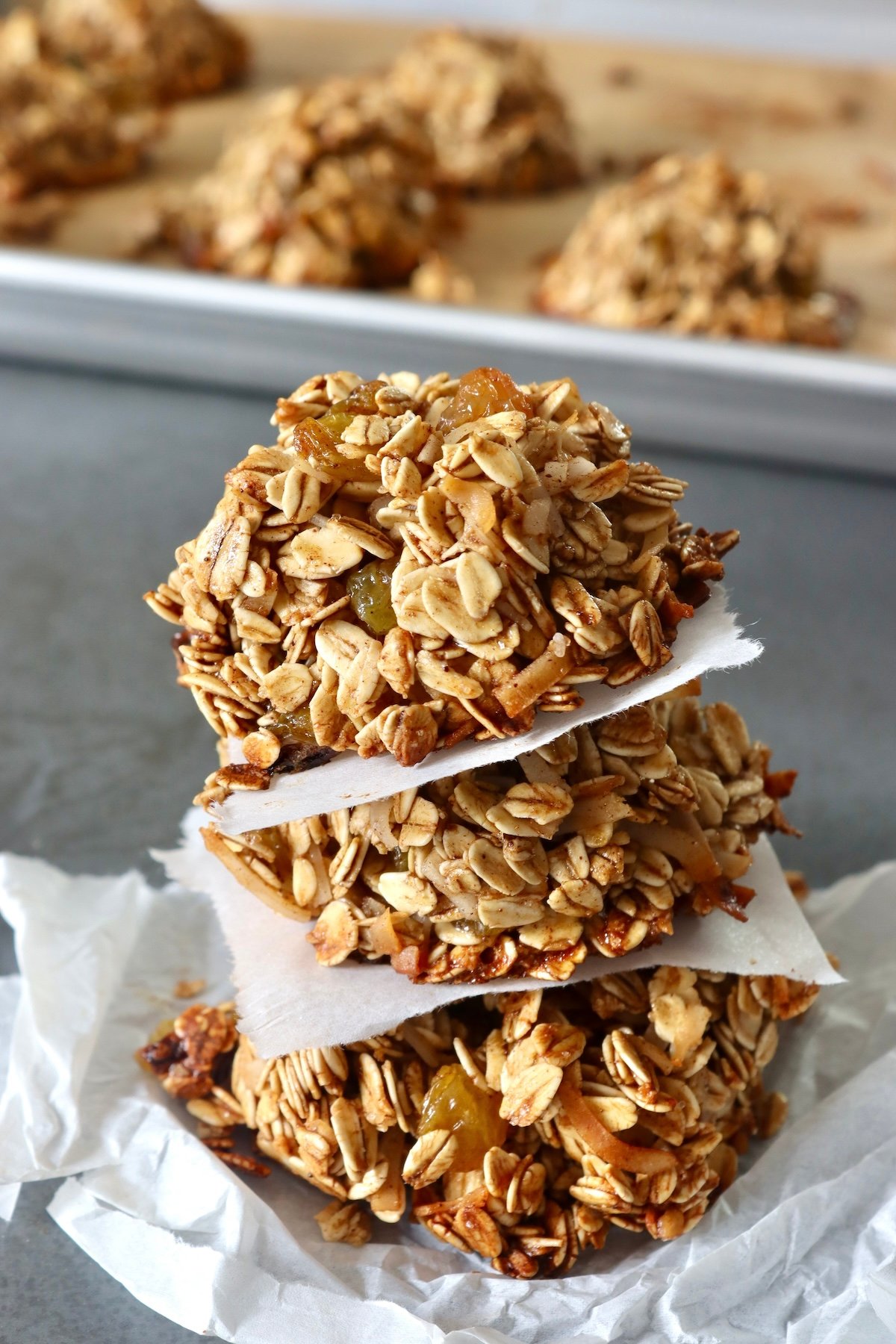 Stack of 3 granola cookies with a square of parchment between each one.