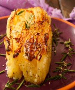 thick slice of potato pave on purple plate with rosemary