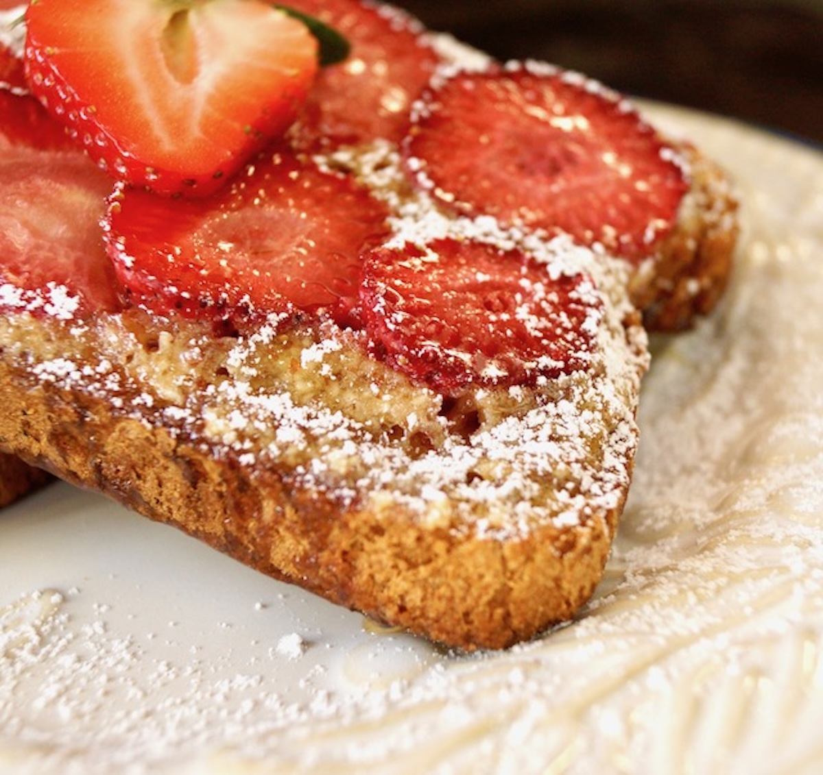 Strawberry-Frangipane-Toast-Recipe Toast with strawberry slices and powdered sugar on white plate.