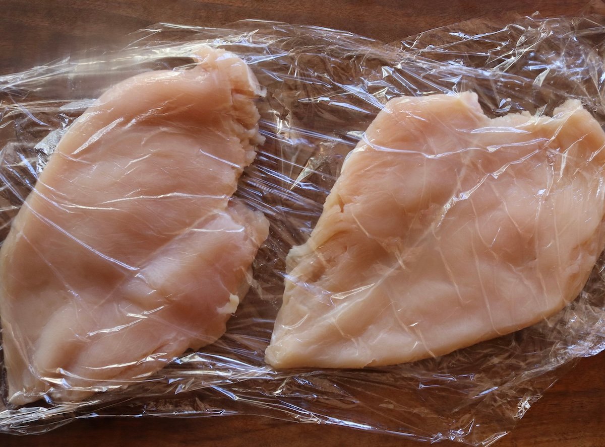 2 boneless, skinless pounded thin, chicken breasts between 2 sheets of plastic wrap.