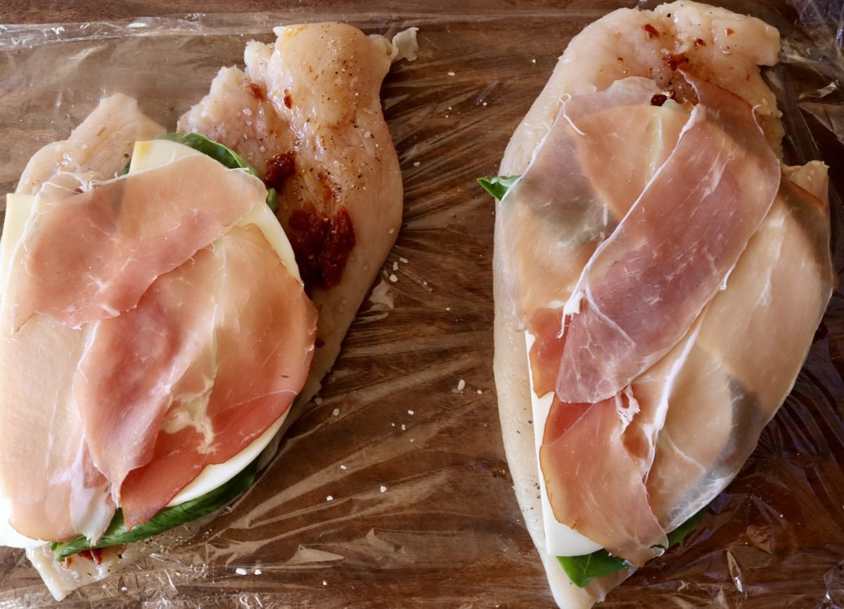 2 pounded chicken breasts with a layer of chopped sun-dried tomatoes, basil leaves, sliced provolone cheese and prosciutto slices on top.