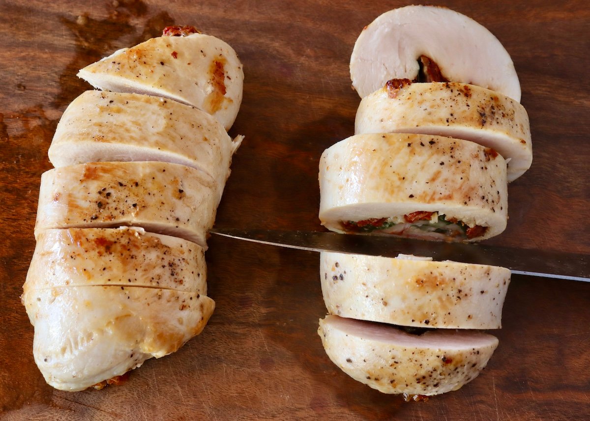 Two cooked and sliced chicken roulades on a cutting board.