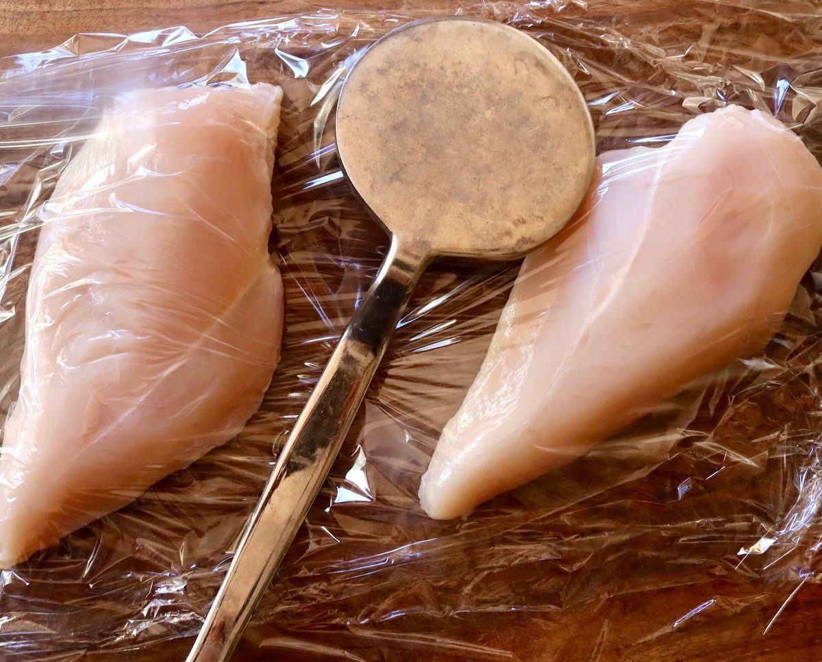 2 boneless, skinless chicken breasts between 2 sheets of plastic wrap with a meat pounder.