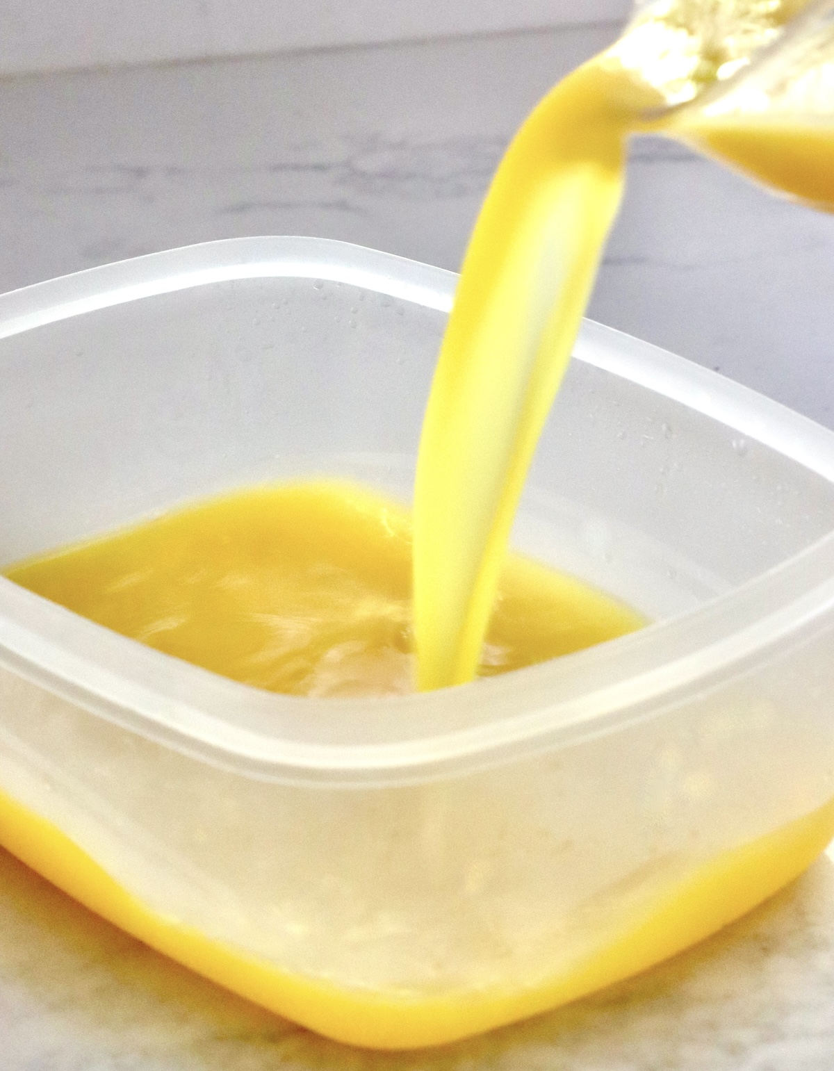 Frozen-Mimosa Orange juice being poured into a plastic rectangular container.
