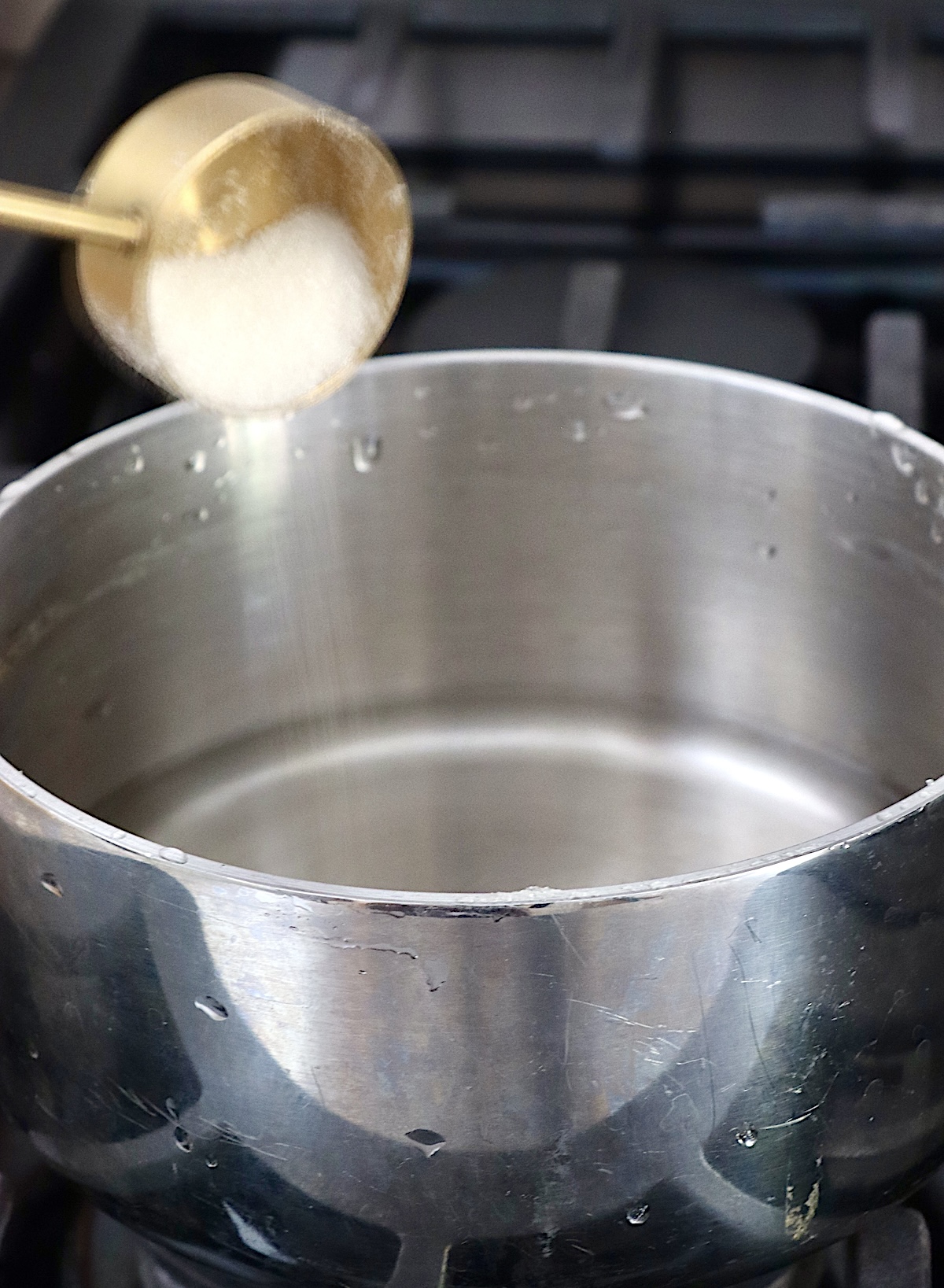 Frozen-Mimosa Sugar being poured into a small saucepan with water.