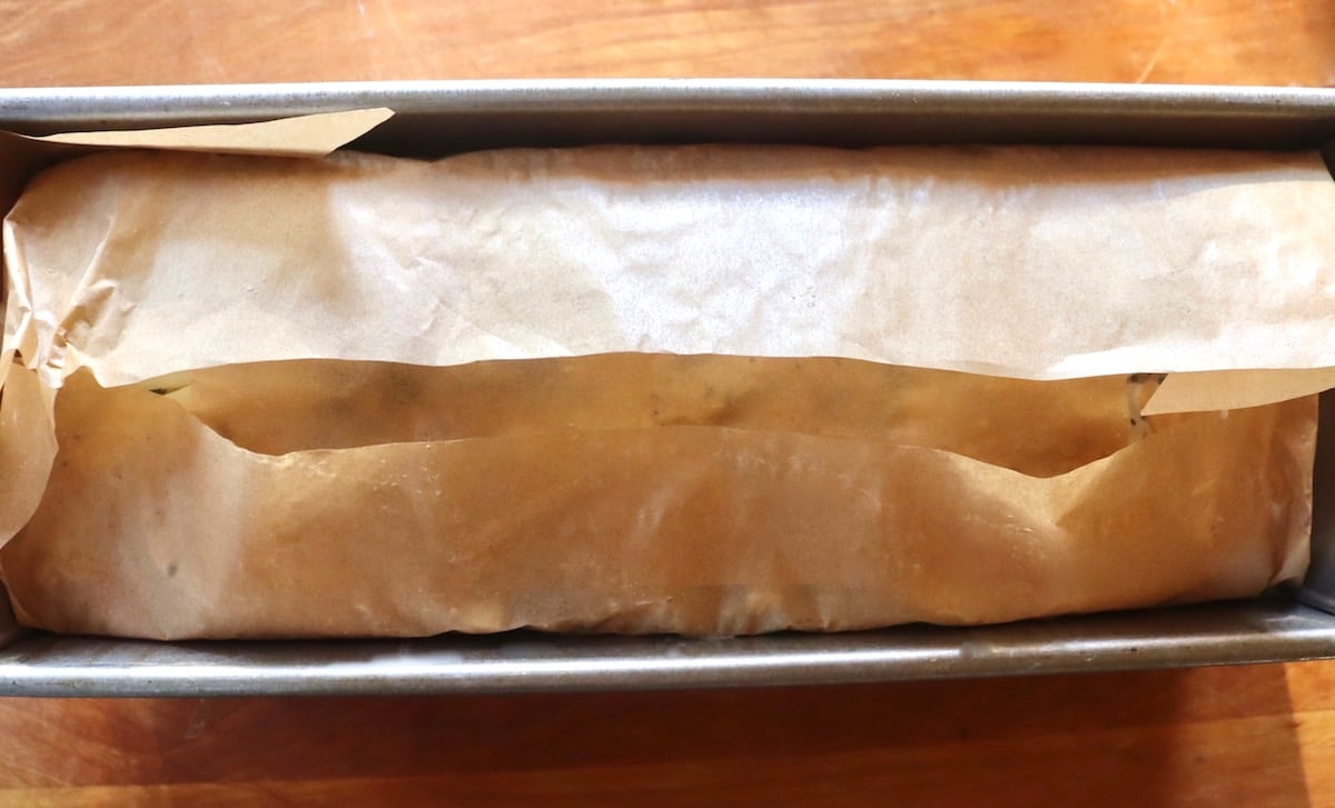 Loaf pan with potatoes (not visible) wrapped in parchment paper.