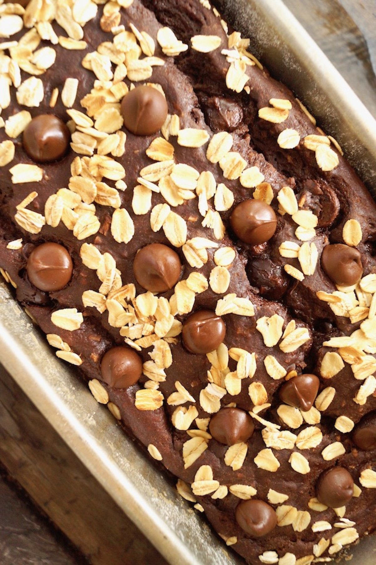 Chocolate breakfast bread in loaf pan with oats and chocolate chips on top,
