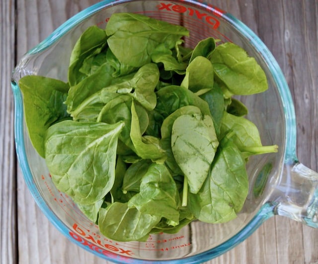 glass measuring beaker with spinach inside