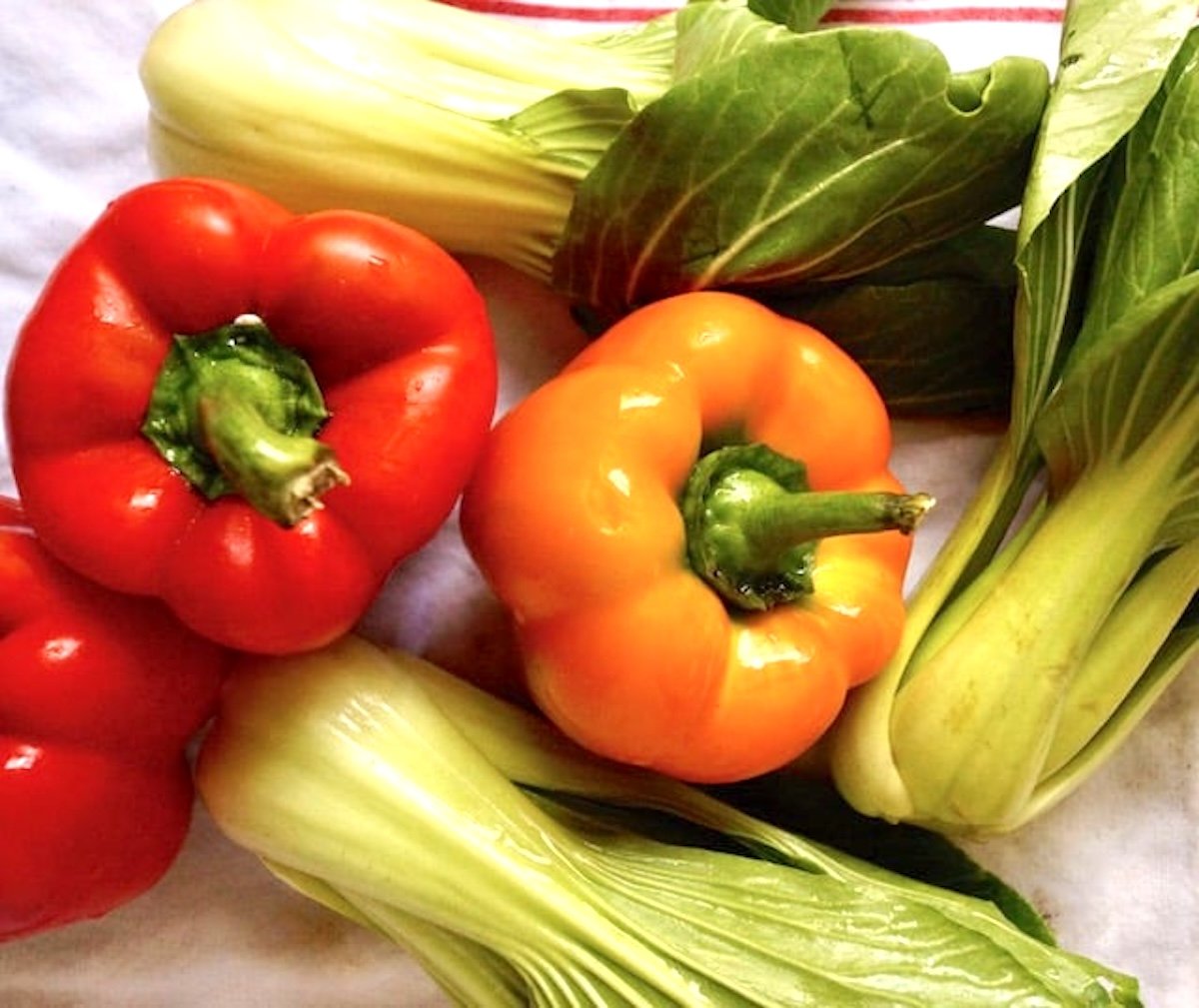red and orange bell pepper and 3 bok choy on white towel