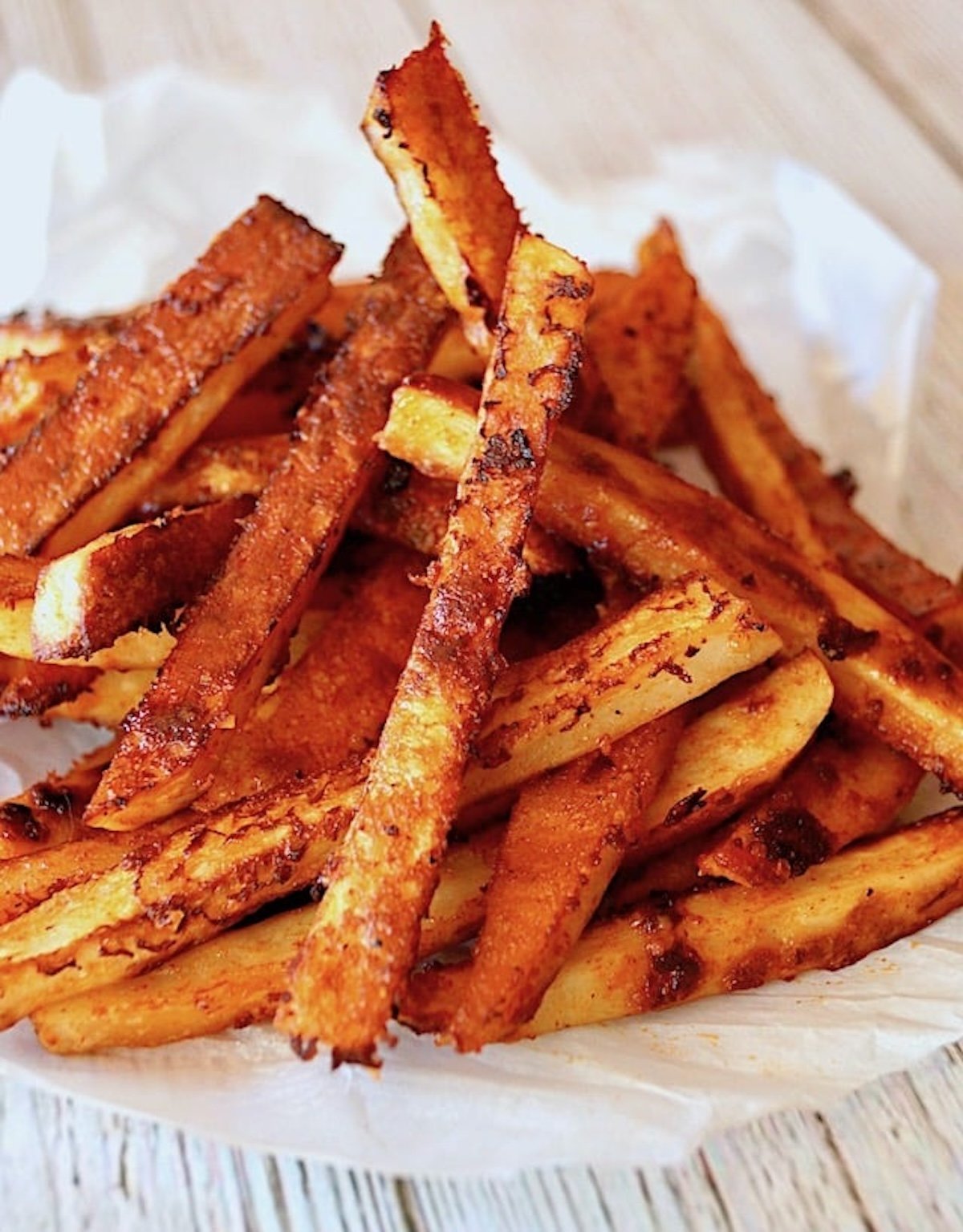 Pile of Parmesan Chipotle French fries on parchment paper.