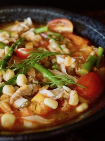 Close up of Summer Fish Stew in black bowl.