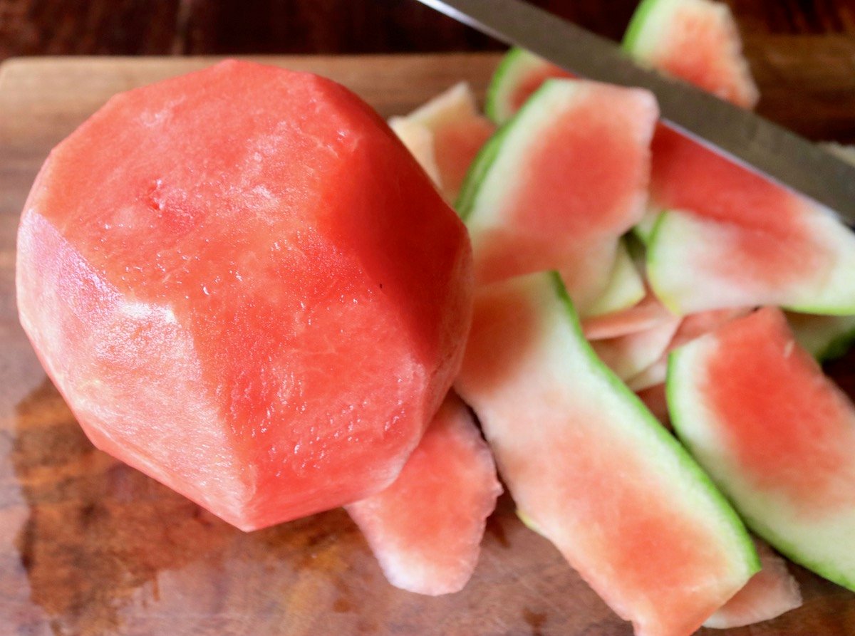 Small watermelon on cutting board without rind.
