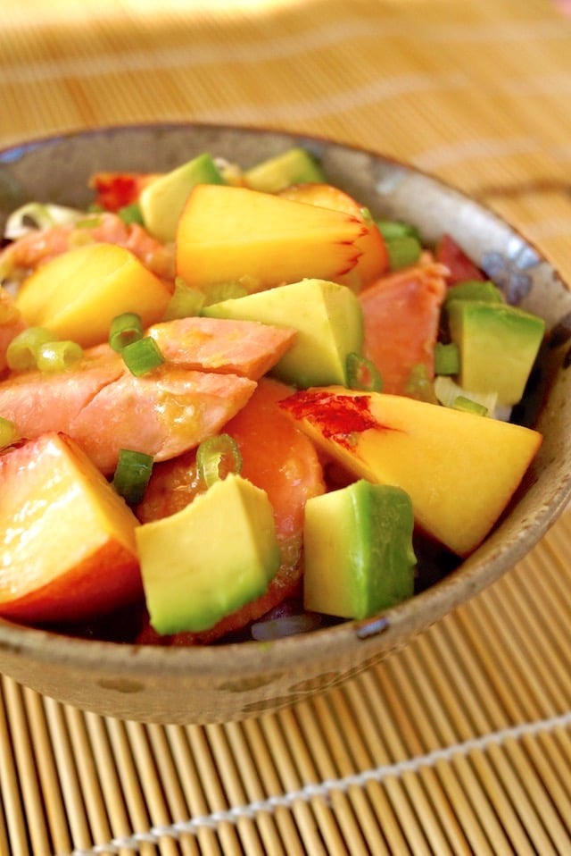 Avocado Salmon Bowl with Peaches in ceramic bowl on sushi mat