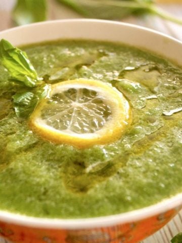 Cold Cucumber Soup with a slice of lemon in orange bowl with white rim